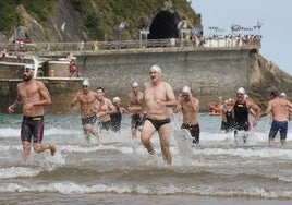 Varios participantes corren en su llegada a Zarautz tras nadar desde Getaria.