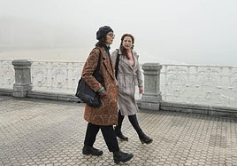 Zuriñe y Fátima caminan por un paseo de La Concha cubierto de niebla el pasado viernes en Donostia.