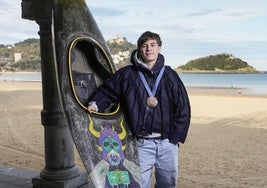 Pau Echaniz posa con la medalla olímpica de bronce en el cuello y su piragua, en los bajos de la playa de La Concha.