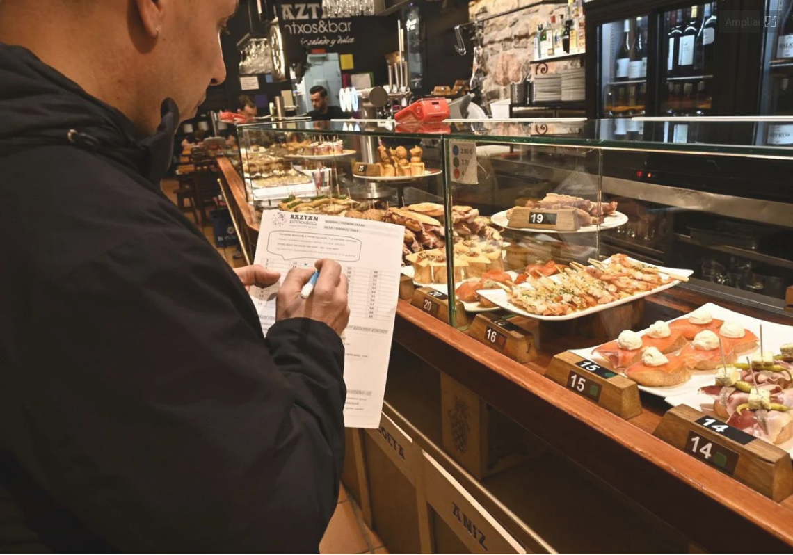 Un cliente rellena el formulario para pedir pintxos en el bar Baztan de la Parte Vieja de Donostia.