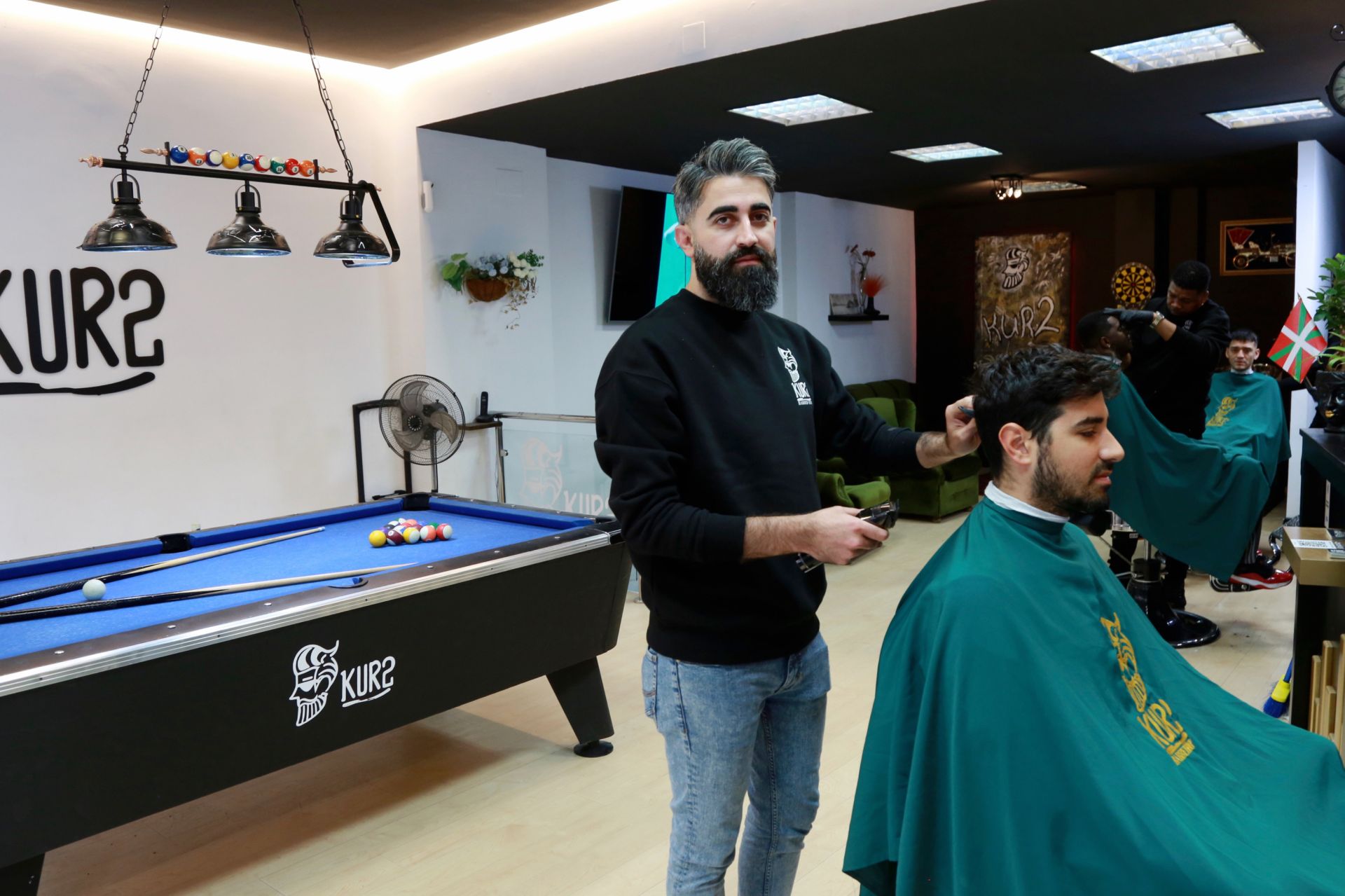 Hakar, que llegó a Gipuzkoa en 2017 tras huir de Siria, atiende a un cliente en una de sus dos barberías en Donostia.