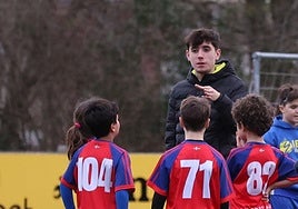 Un monitor de fútbol da instrucciones a unos niños.