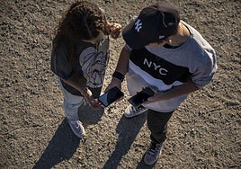 Dos jóvenes observan sus móviles.