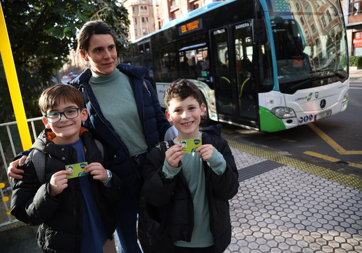 Los mellizos Luca y Telmo, de 9 años, muestran sus tarjetas Mugi en compañía de su madre, Ainara Nieto, en la parada de Jai Alai.