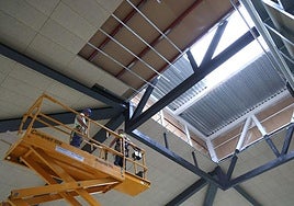 Dos obreros realizan trabajos en la cubierta del edificio Pescadería de la Bretxa.