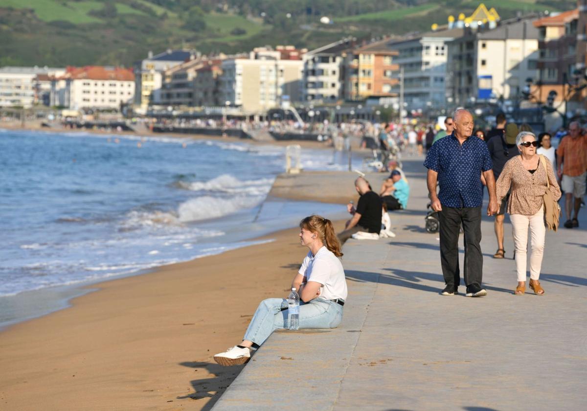 Turistas pasean por el malecón zarauztarra en un día de marea alta.