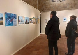 Varias personas mirando los cuadros expuestos en Torre Luzea por el alumnado de Artezaleak.