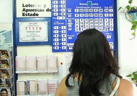 Una mujer comprueba la combinación ganadora de la Bonoloto en una administración de Lotería.