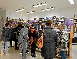 Grupo de personas en la recién inaugurada sección de feminismo en la biblioteca.