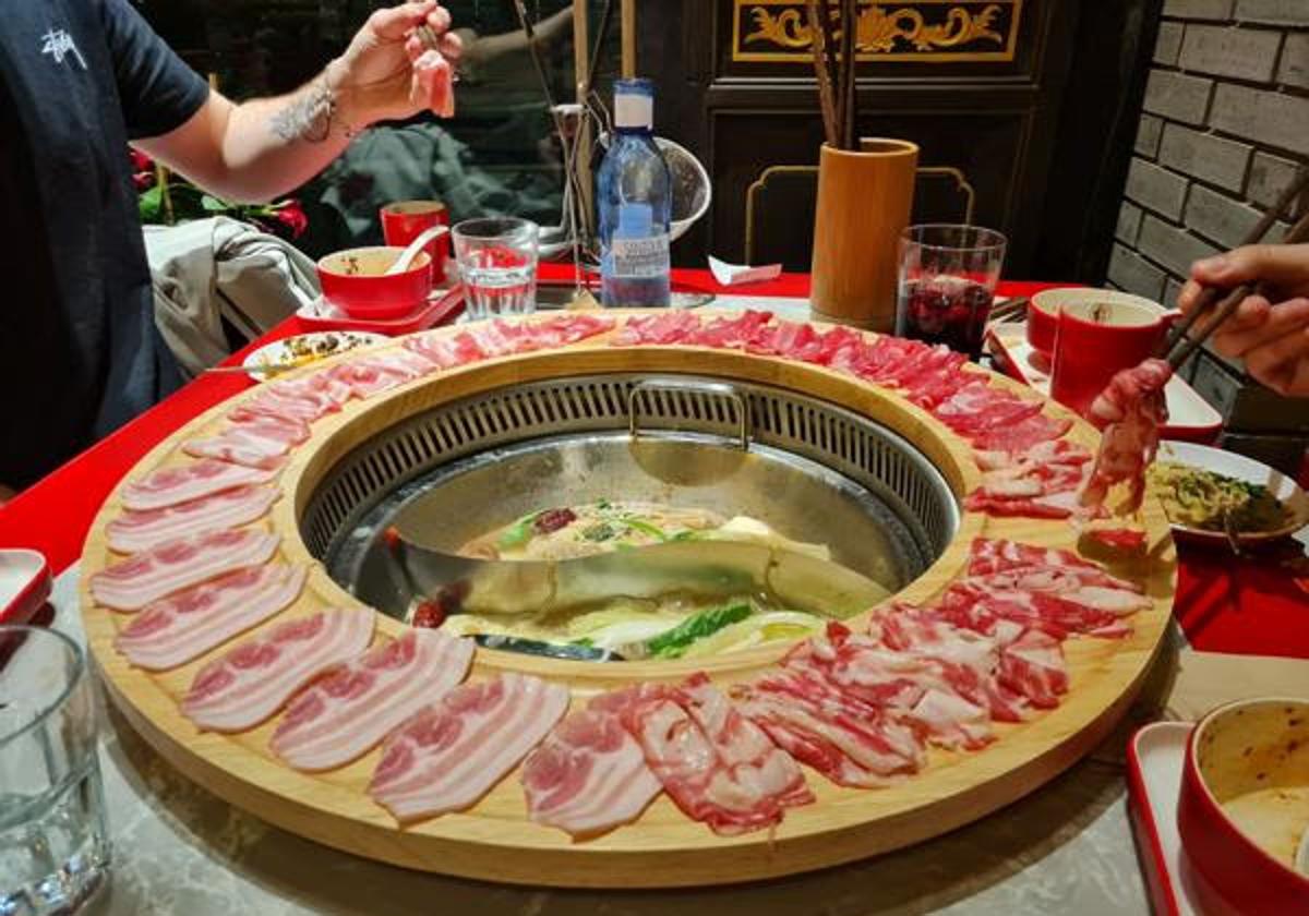 Pescar fideos con palillos en una olla