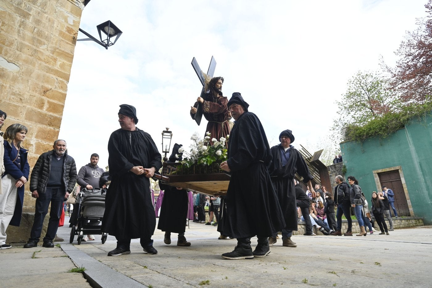 Procesión. Decenas de personas observan cómo los costaleros llevan uno de los pasos hasta la iglesia.