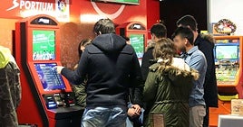 Varios jóvenes realizan apuestas en las máquinas en un salón de juegos.