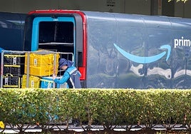 Un trabajador de Amazon junto a una furgoneta de reparto de la compañía.