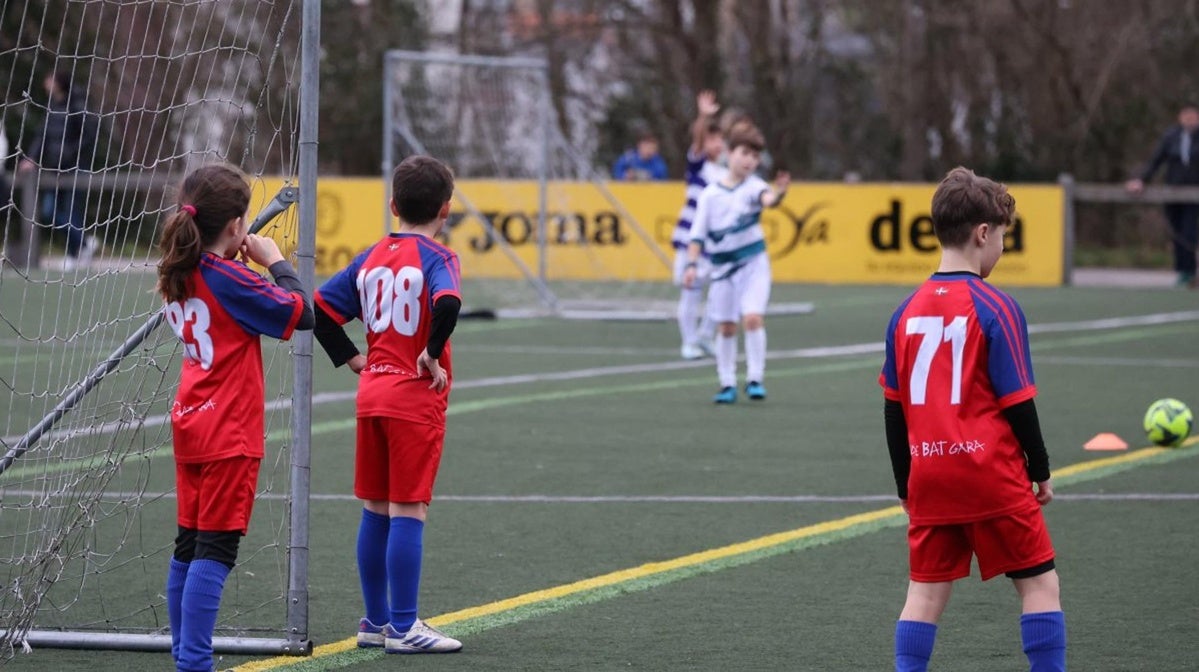 Niños y niñas juegan a fútbol en una actividad de deporte escolar organizada en un recinto donostiarra.
