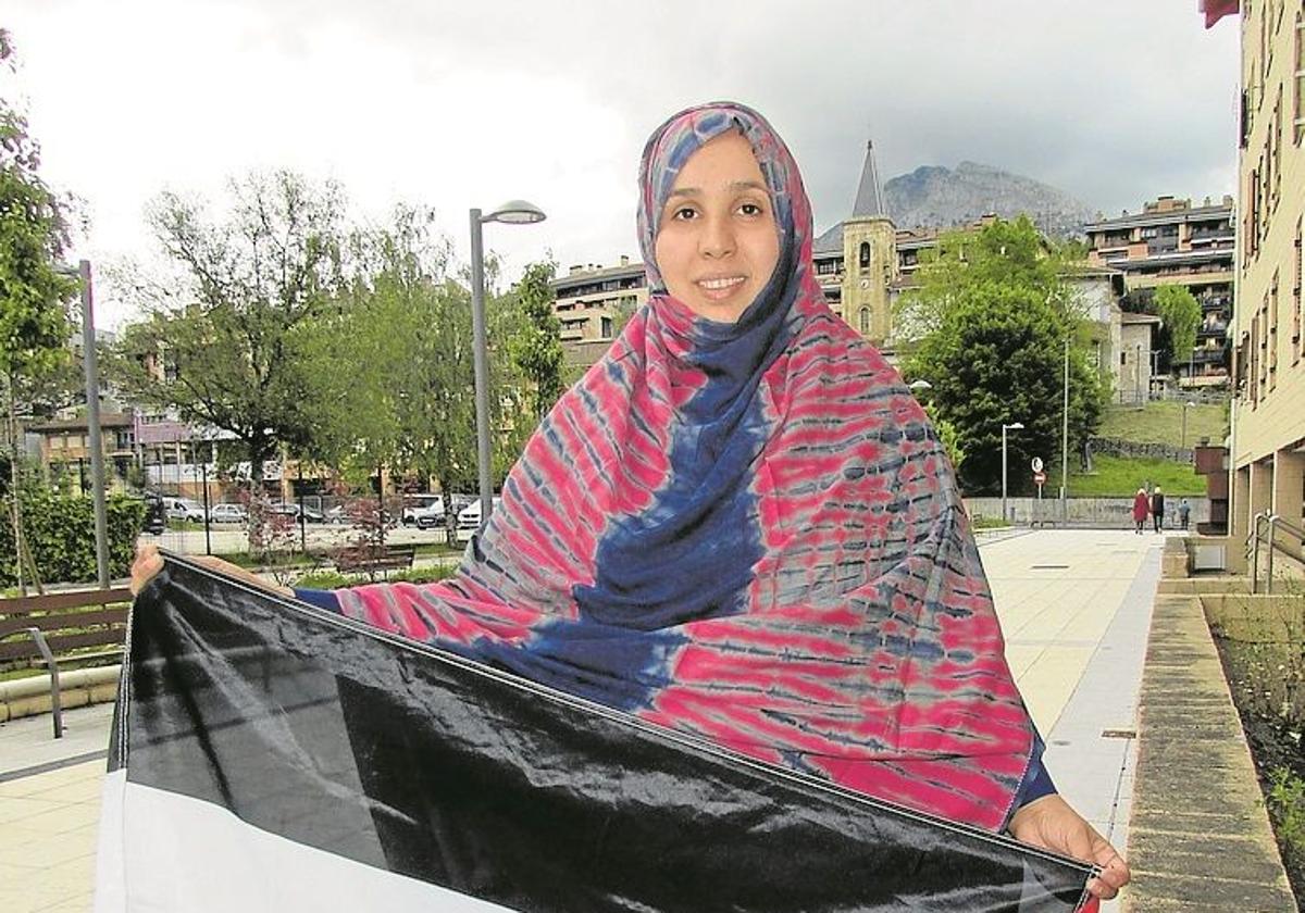 La joven malika posa con la bandera de su pueblo en Arrasate.