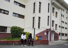 Dos migrantes sentados junto a la entrada del centro Larraña Etxea, donde la víctima residía desde hacía una semana.