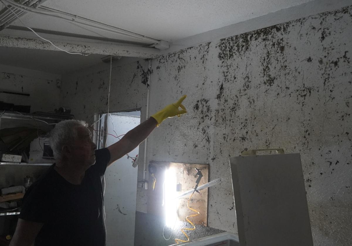 Un vecino señala la altura hasta la que llegó ayer el agua, prácticamente hasta el techo