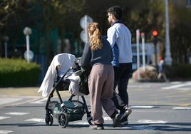Una pareja joven pasea en un cochecito a su bebé.
