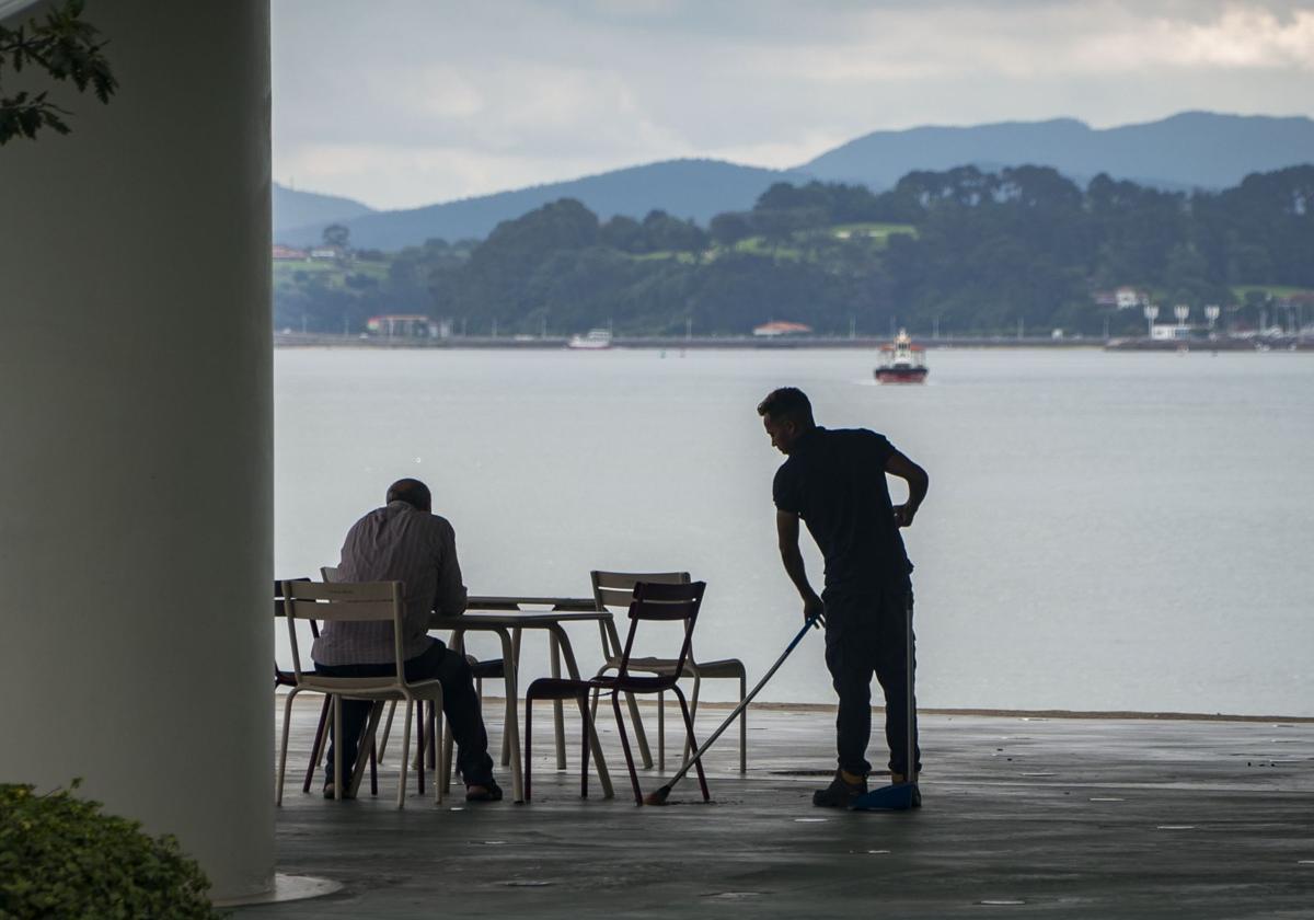 Un camarero trabaja en una terraza ante un cliente.