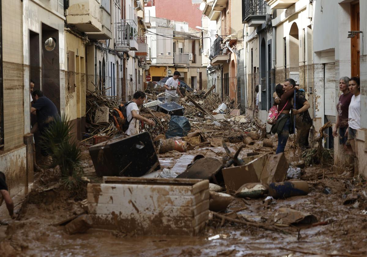 Varias personas trabajan en labores de limpieza y desescombro en una calle del municipio de Paiporta, en Valencia, uno de los más afectados por la DANA del pasado 29 de octubre.