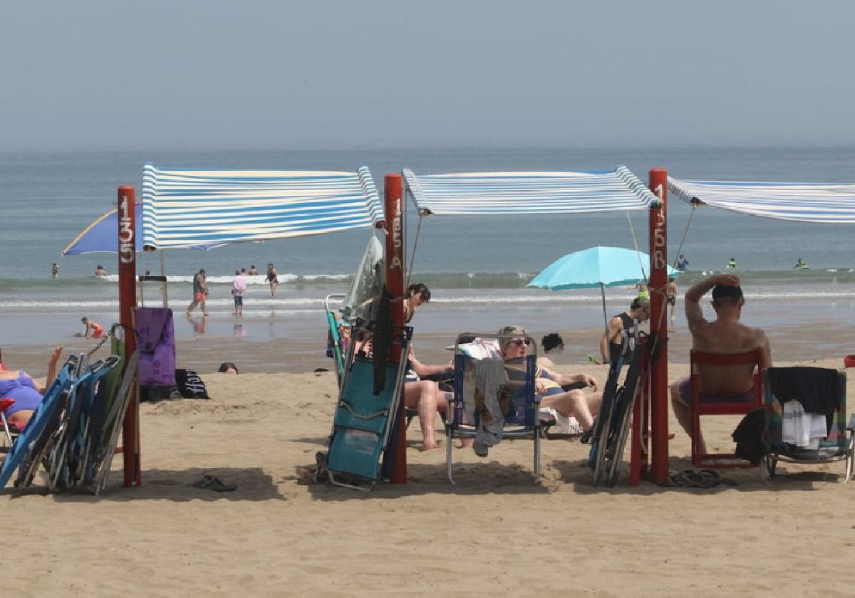 Varias personas se protegen del sol bajo los toldos de la playa de Deba, el pasado verano.