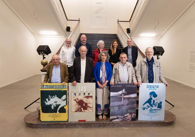 Los directores sujetan los carteles de sus películas acompañado de representantes de las instituciones que participan en el proyecto y de la escritora Arantxa Urretabizkaia.