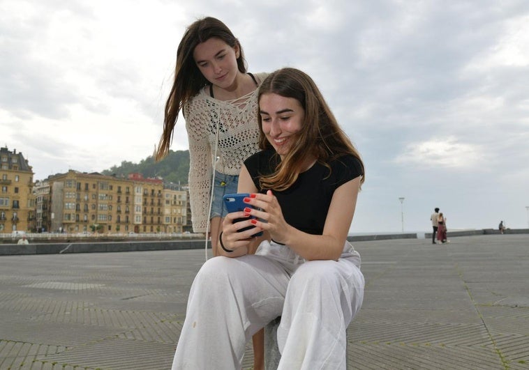 Maddi Garate, estudiante que ha sacado la mejor nota de Selectividad de Euskadi, consulta su calificación en el teléfono móvil bajo la mirada de una amiga Alaine este miércoles en San Sebastián.
