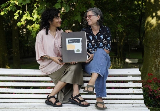 Ainara Martín y Usoa Zumeta sostienen un cuaderno que contiene dibujos de Koldobika Jauregi.