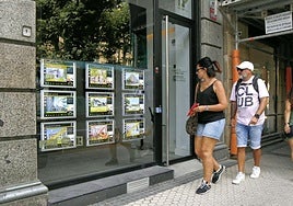 Una pareja pasa por delante de una inmobiliaria en Donostia.