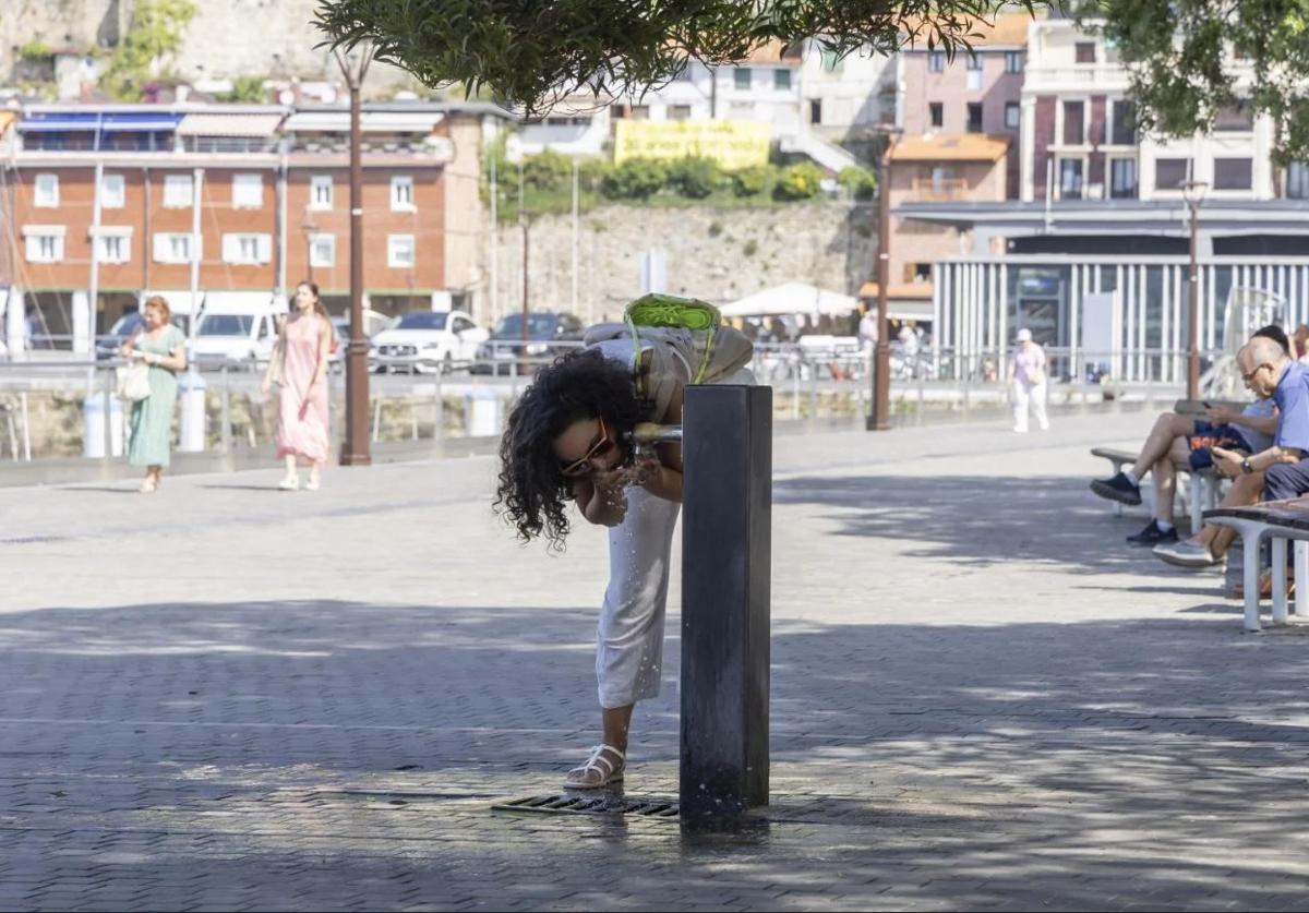 Una joven bebe agua de una fuente pública de San Sebastián.