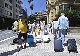 Varios turistas cargan maletas por San Sebastián.