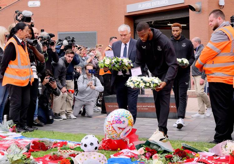 Beto coloca un ramo de flores en el altar de homenaje a Diogo Jota y André