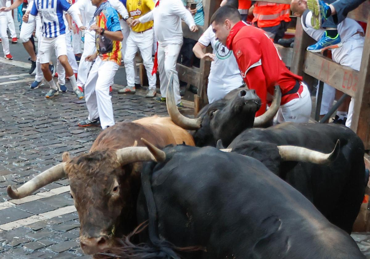 Uno de los toros de La Palmosilla engancha a un mozo contra el vallado en la curva de Mercaderes.