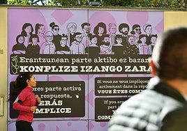 Una persona observa un cartel de condena a las agresiones machistas colocado en una calle de San Sebastián.