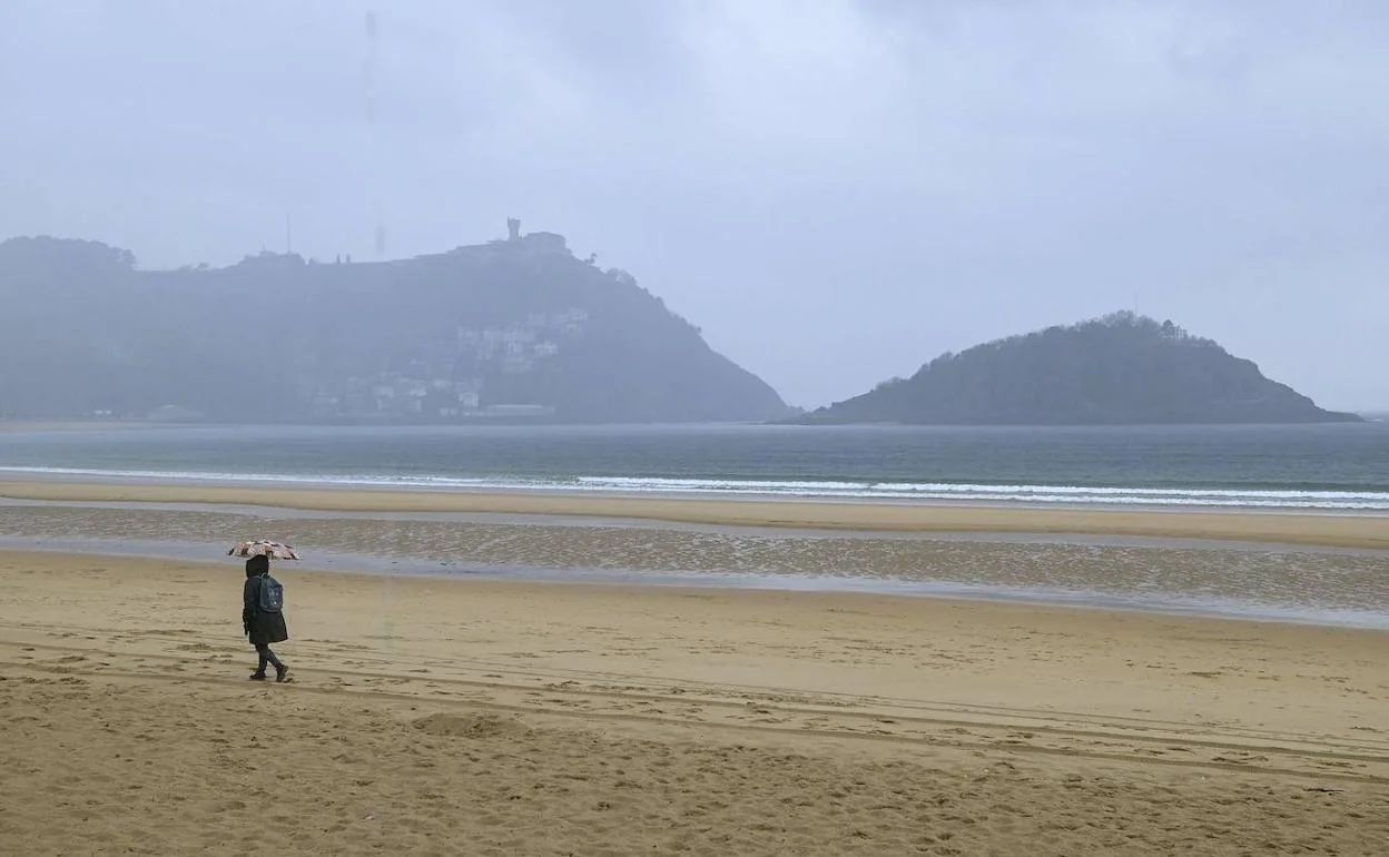 Una mujer pasea por La Concha a pesar del sirimiri.