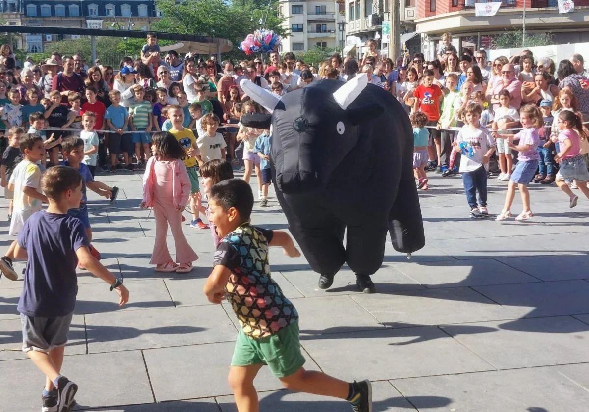 Niños corren perseguidos por un toro hinchable en Irun.