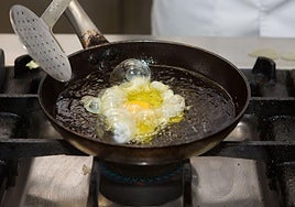 Un cocinero fríe un huevo en una sartén.
