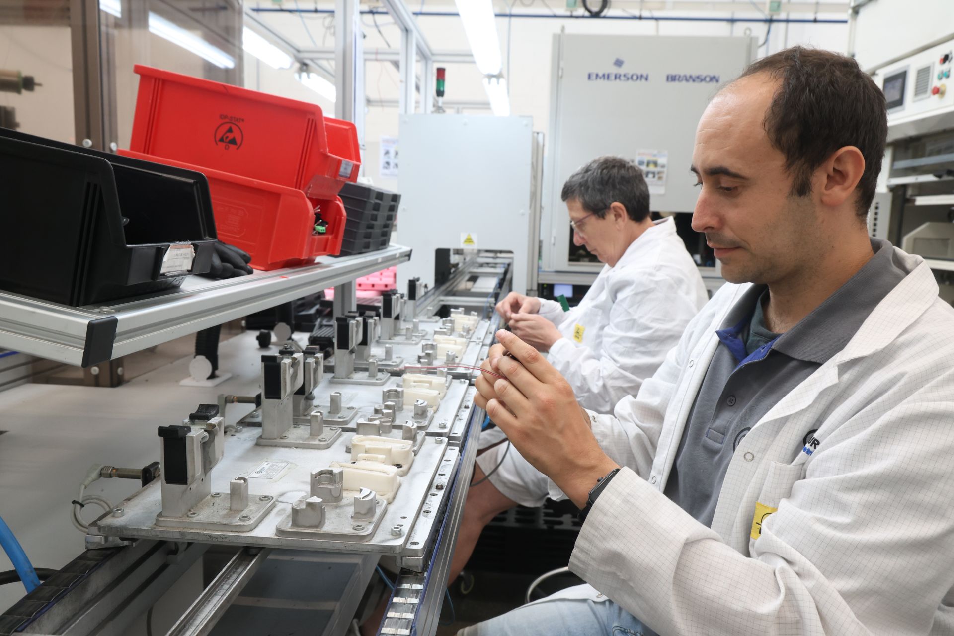 Dos trabajadores del área industrial de Gureak ensamblan la pieza que va en el retrovisor de los Porche para iluminar el suelo cuando se abre la puerta.