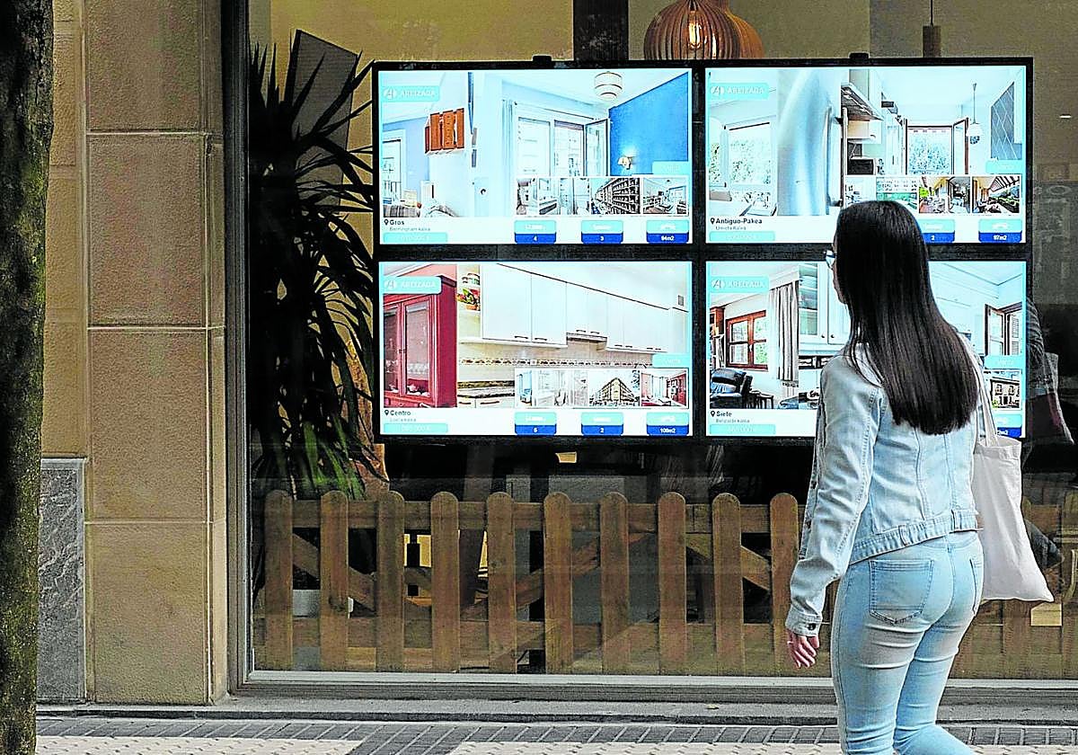 Una joven frente el escaparate de una agencia inmobiliaria