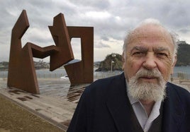 El artista donostiarra posando junto a la escultura 'Construcción vacía' de Jorge Oteiza en el Paseo Nuevo, en una imagen de archivo.