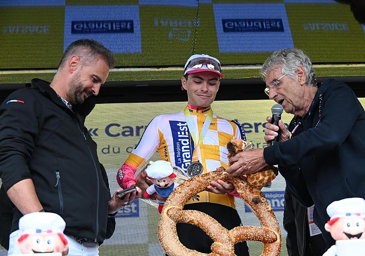 Markel Beloki sostiene un gigante pretzel en el podio del Tour de Alsacia.