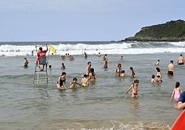 Varios bañistas disfrutan de las olas en Zurriola bajo la vigilancia de los socorristas.