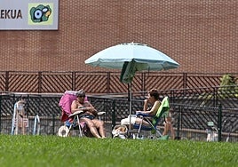Dos mujeres se protegen del sol bajo una sombrilla en Elgoibar.
