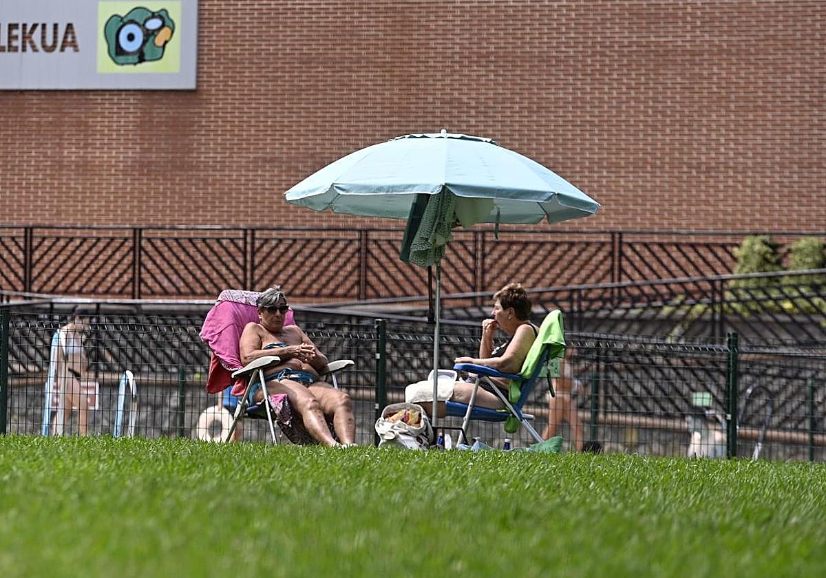 Dos mujeres se protegen del sol bajo una sombrilla en Elgoibar.