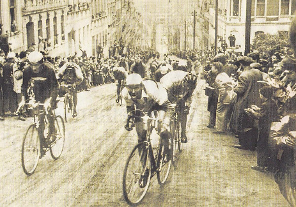 Ciclistas se retuercen en un paso de la Carrera de la Paz por el muro de Meerane.