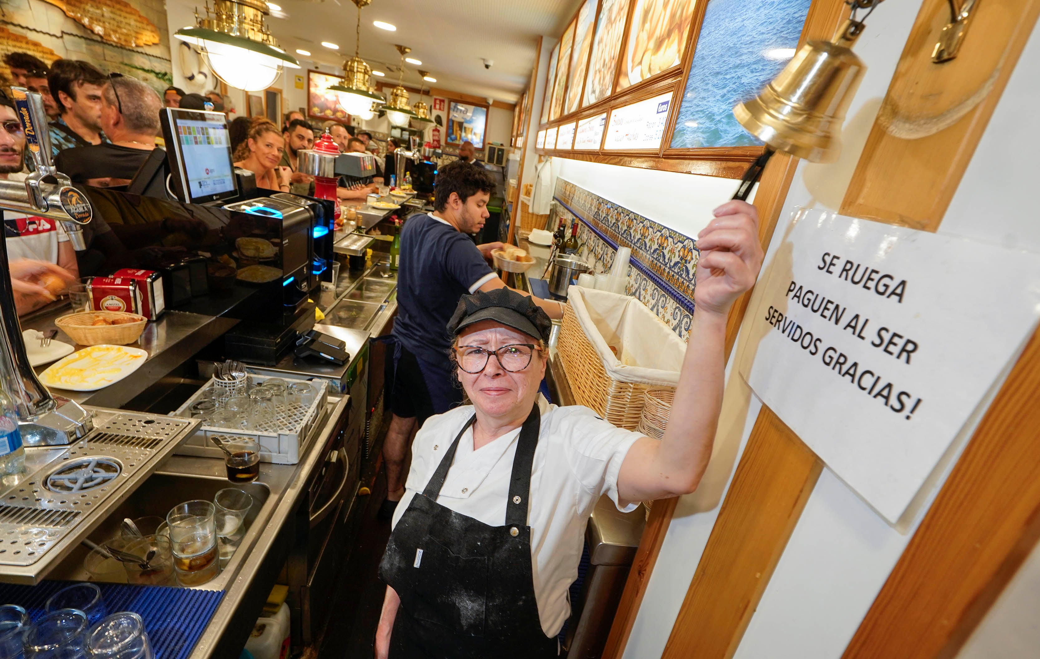 Coro López Iñarra, encargada de la Mejillonera, tocando su icónica campana en el bar.