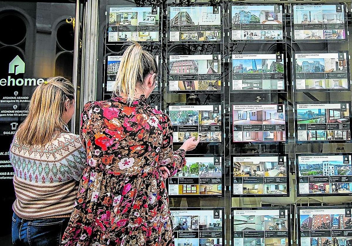Dos mujeres observan el escaparate de una inmobiliaria. Estas han canalizado en vivienda usada ocho de cada diez ventas.