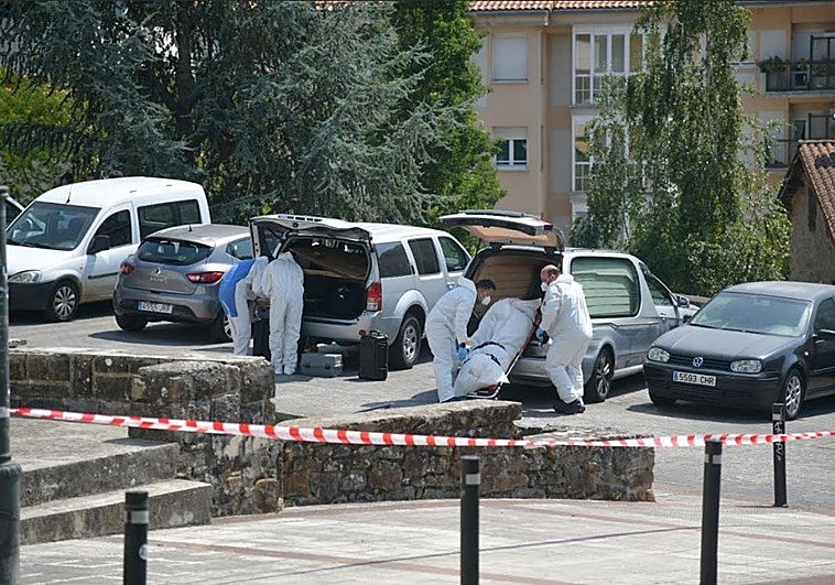 El cadáver es introducido en un coche fúnebre.