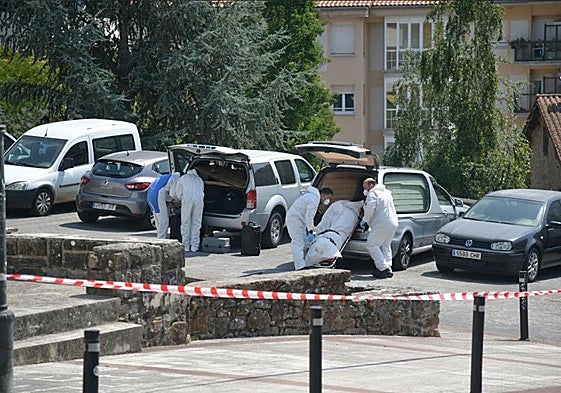 El cadáver es introducido en un coche fúnebre.