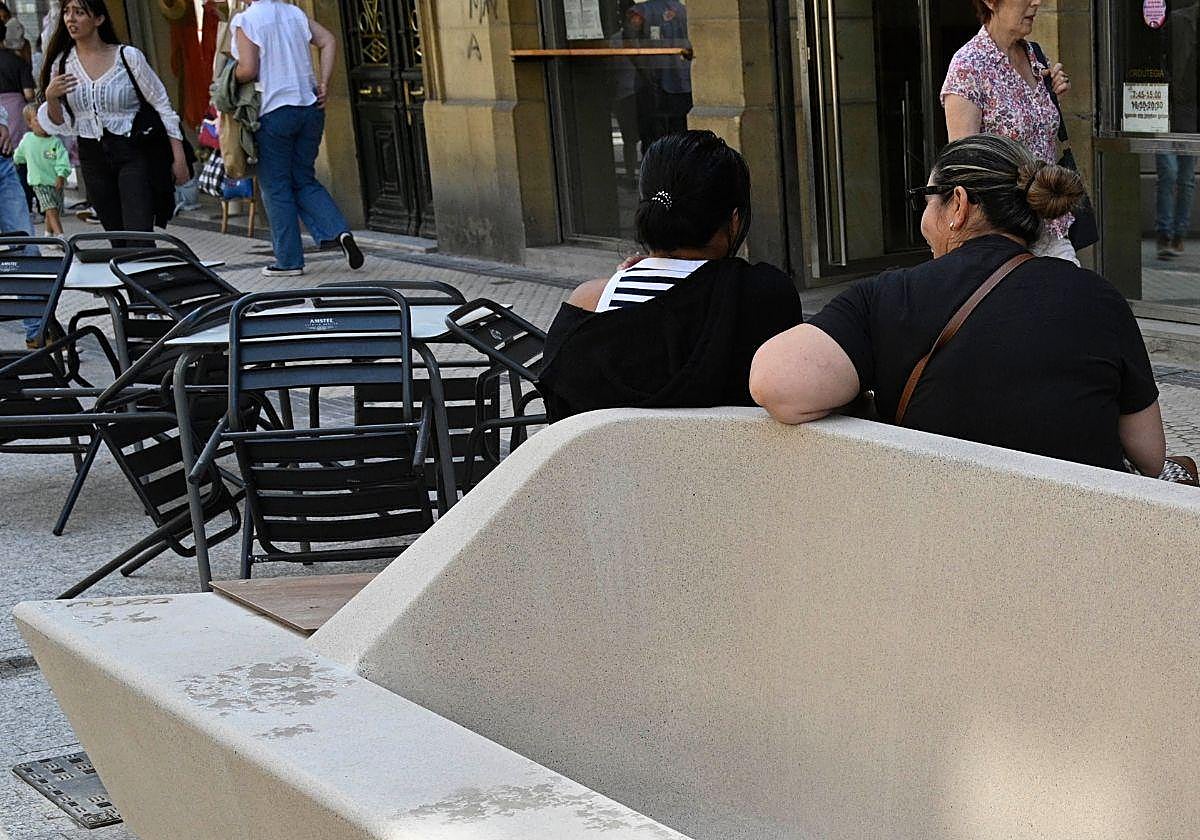 Nuevos bancos públicos instalados en la calle Easo junto a las mesas de la terraza de un bar.